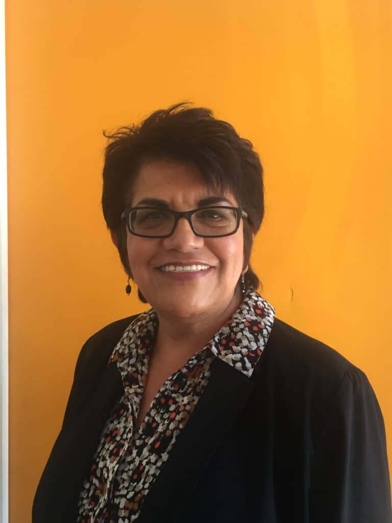 Betty smiling in front of orange background