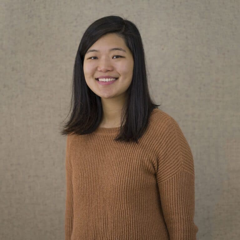 Cindy Lee smiling in front of grey/beige background