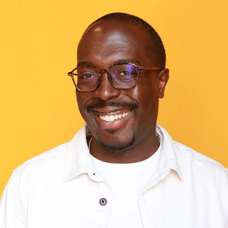Charles smiling in front of orange background